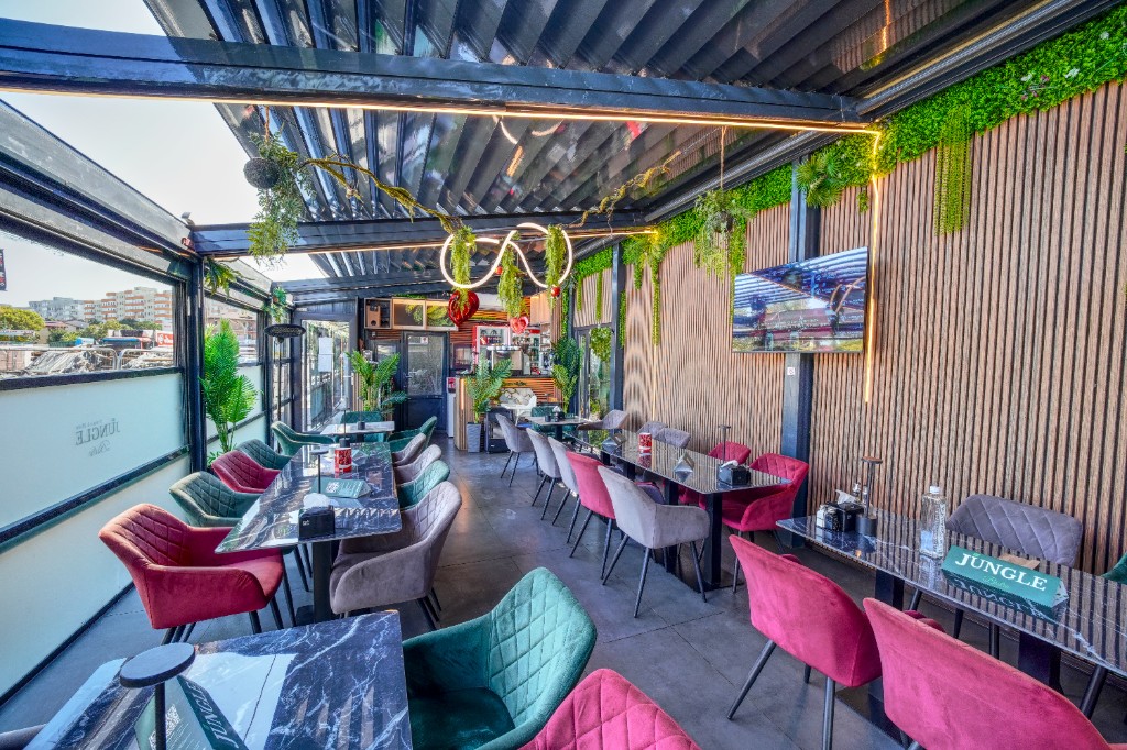Terasă Jungle Bistro spre ferestre, mese negre și fotolii colorate